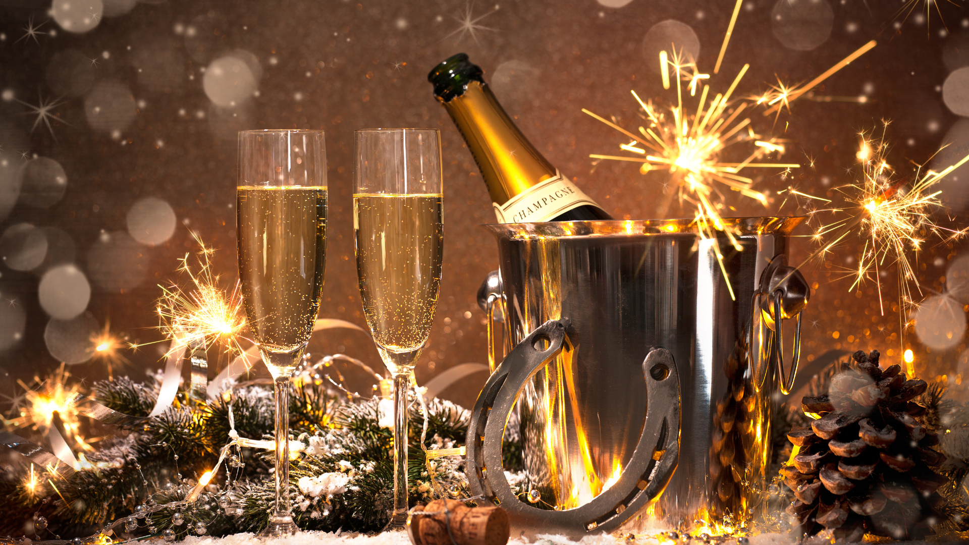 Festive champagne celebration with sparklers, two glasses, and a bottle in a bucket surrounded by holiday decor.