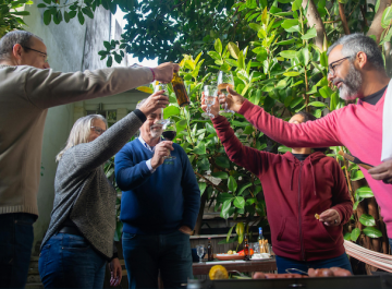 Group of friends toasting with drinks in a lush garden setting, enjoying a celebratory gathering.